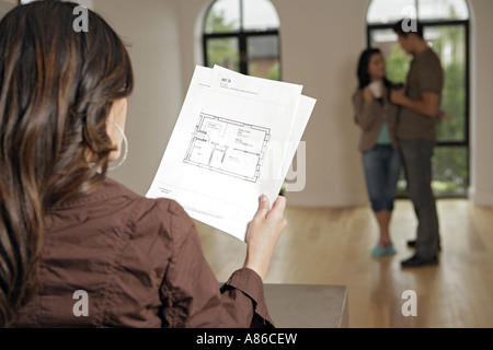 Junge Frauen halten während paar Papier im Hintergrund, Rückansicht Stockfoto