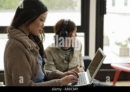 Frau, die Arbeiten am Laptop, Mann, Musik hören Stockfoto