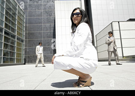 Eine Frau wirft während zwei Männer im Hintergrund zu sehen sind. Stockfoto
