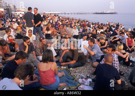 Brighton Beach Party 2000s UK. Die Menschenmassen versammeln sich, um zu beobachten, wenn die Dämmerung in einem Open-Air-Kino einbricht. Palace Pier in der Ferne. East Sussex England HOMER SYKES Stockfoto