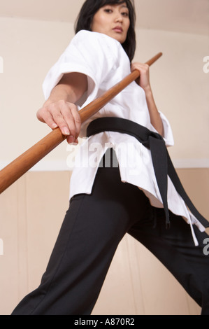 Frau Kampfkünstler mit einem Stock in eine defensive Haltung Stockfoto