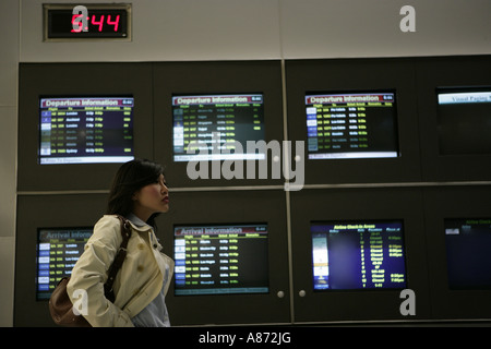 Eine junge Frau steht neben TV-Bildschirme. Stockfoto