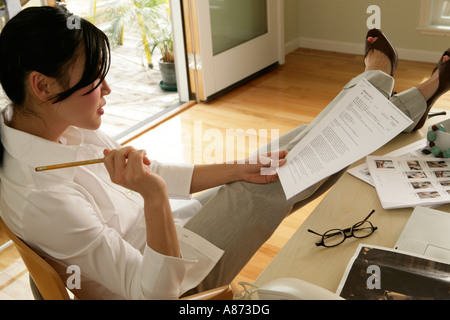 Junge Frau sitzend auf Stuhl Papier, seitliche Ansicht Stockfoto