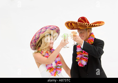 Braut und Bräutigam tragen Sombreros und Blumengirlanden und Toasten Stockfoto