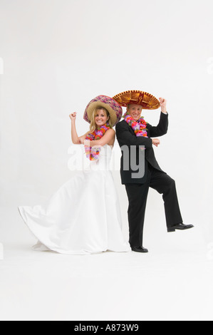 Braut und Bräutigam tragen Sombreros und Blumengirlanden beim Tanzen Stockfoto