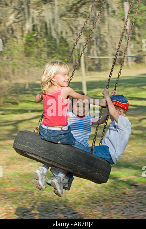 Drei kleine Kinder, die an einem sonnigen Sommertag in Florida, USA, auf einer Reifenschaukel schwingen Stockfoto