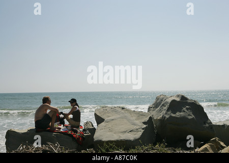 Mann und Frau auf Felsen in der Nähe von Meer Stockfoto
