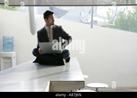Mann sitzt im Lotussitz mit einem laptop Stockfoto