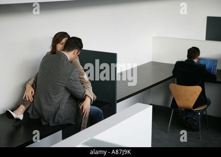 Drei Menschen in einem Büro, zwei umarmen Stockfoto