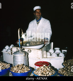 Lokale Anbieter verkauft Schnecken durch Lampe Licht in der Nacht auf Djemma el Fna Platz in Marrakesch, Marokko Stockfoto