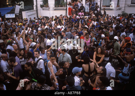 Beim jährlich stattfindenden Notting Hill Carnival West London um die 1995 1990er Jahre im Vereinigten Königreich HOMER SYKES tanzen Menschenmassen auf der Straße Stockfoto