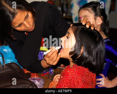 Mutter setzen Make-up auf Tochter bereit für Holi Leistung im hinduistischen Zentrum Wimbledon London England Stockfoto