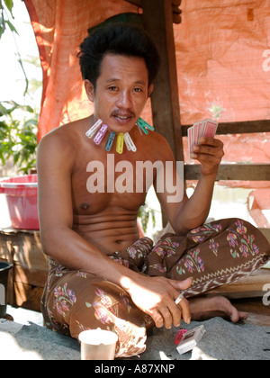 Mann mit Wäscheklammern auf seinem Gesicht verliert in Glücksspiel, slum Gegend, Surabaya, Java, Indonesien Stockfoto