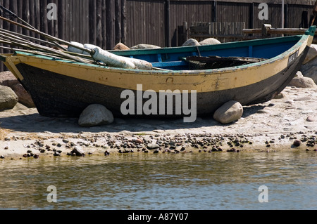 Traditionelles polnisches Fischerboot mit gelbem und schwarzem Rumpf an einem felsigen Ufer am Wasser. Stockfoto