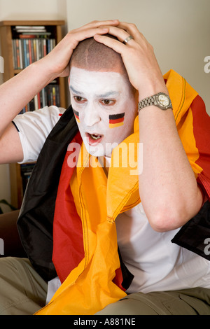 -Modell veröffentlicht. Deutsche Fußball-Fan sitzt auf dem Sofa vor dem Fernseher suchen aufgeregt, als Team gerade verloren hat. Stockfoto