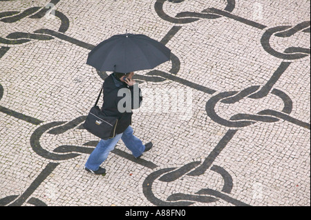 ein Mann zu Fuß und spricht in sein Handy hält einen Regenschirm in den Regen, Aveiro, portugal Stockfoto