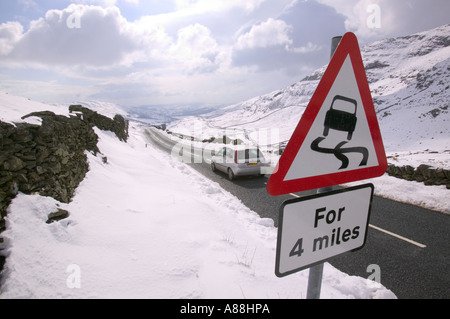 ein Autofahrer und Warnung Zeichen auf Kirkstone pass im Winter, rote Geröllhalden, Lake District, Cumbria, UK Stockfoto