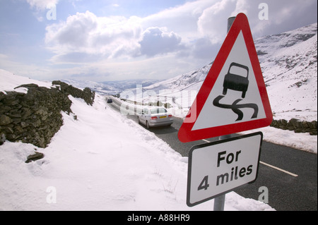 ein Autofahrer und Warnung Zeichen auf Kirkstone pass im Winter, rote Geröllhalden, Lake District, Cumbria, UK Stockfoto