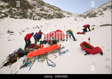 eine Bergrettung retten einen gefallenen Wanderer auf roten Geröllhalden, Lake District, Cumbria, UK Stockfoto