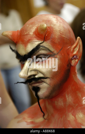 Männlicher gehörnter Teufel mit roter und goldener Gesichtsfarbe, spitzen Ohren, langem schwarzen Schnurrbart und edlem Bart. Stockfoto