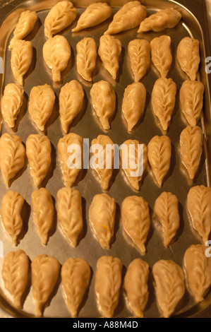 Tibetische Knödel auf einem Metalltablett, ordentlich in Reihen angeordnet, mit traditionellen blattförmigen Falten vor dem Kochen. Stockfoto