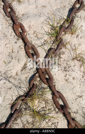 Zwei halbe begraben rostigen Eisenketten Charakter X auf Sand Stockfoto