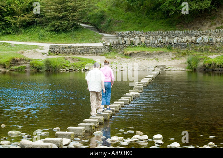 Zwei Personen überschreiten Trittsteine auf dem Fluß Wharfe bei Bolton Abbey, Wharfedale, Yorkshire Dales National Park, England, UK Stockfoto