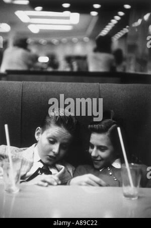 Teenager-Jungen und Mädchen sitzen in einer Kabine in einem 1950-Apotheke teilen Soda auf ein Datum Stockfoto