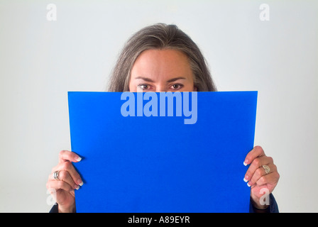 Blick auf eine reife Frau mit einem leeren blauen Schild vor ihrem Gesicht Stockfoto