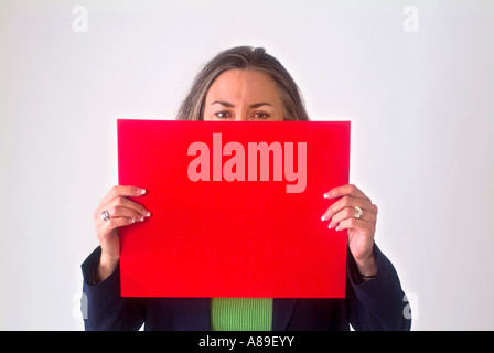 Blick auf eine reife Frau mit einem leeren roten Schild vor ihrem Gesicht Stockfoto