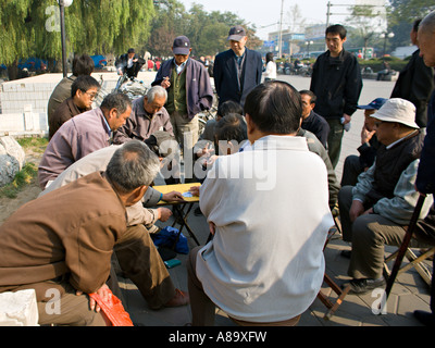 CHINA Peking A Menge der chinesischen Männer versammelt, um ein Kartenspiel auf einem tragbaren Tisch auf dem Bürgersteig zu sehen Stockfoto