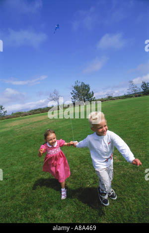 Jungen und Mädchen laufen mit Drachen im park Stockfoto