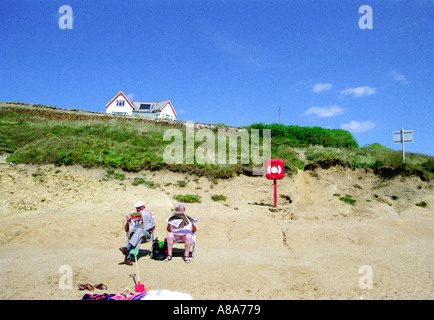 Älteres Ehepaar auf den Liegestühlen am Strand von Burton Bradstock Dorset-England Stockfoto