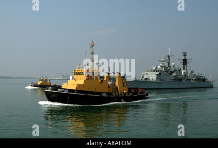 SERCO Denholm betrieben Schiff Schlepper Bustler A225 im Gange eskortierte das Schiff der Royal Navy HMS Gloucester in Portsmouth Stockfoto