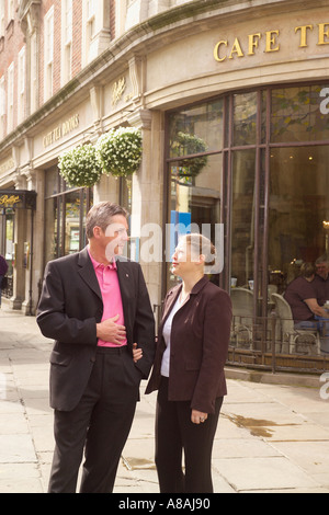 Ein Paar, das Arm in Arm mit dem Bettys Cafe und den Teestuben draußen läuft. York Großbritannien Stockfoto