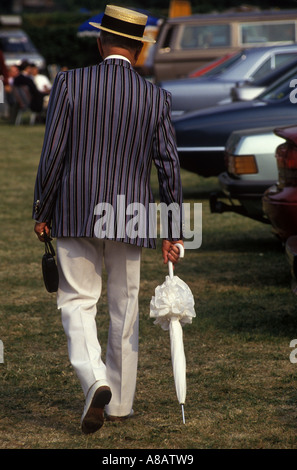 1980er Jahre Mann in Strohbootmütze und Ruderclub-Blazern in Henley Royal Regatta, mit dem Sonnenschirm seiner Frau Henley auf der Themse 1985 UK HOMER SYKES Stockfoto