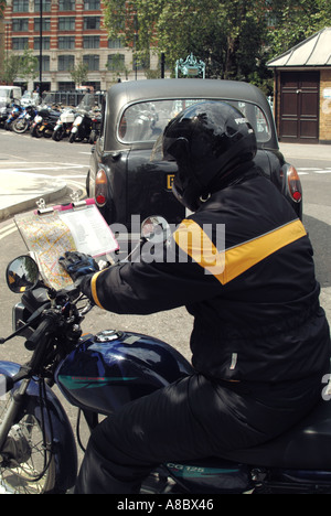 Londoner Taxicab-Auszubildender parkt und sitzt auf einem kleinen Motorrad und studiert die Karte auf dem Klemmbrett als Vorbereitung auf seinen Wissenstest England UK Stockfoto