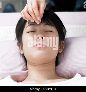 Chinesische Medizin orientalischen Medizin Hand Anwendung von Akupunktur auf Gesicht des Patienten Stockfoto