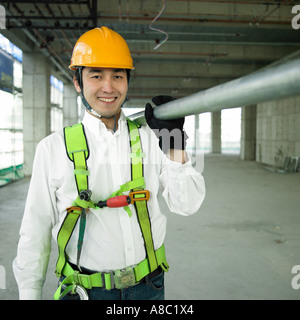 Legen Sie beim Bau ein Arbeitnehmers hält einen verstärkenden Stab auf die Schulter Stockfoto