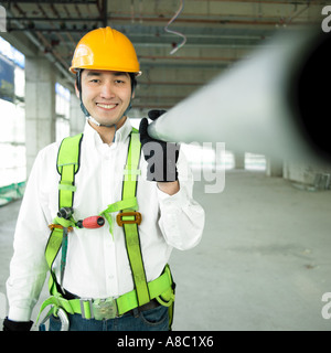 Legen Sie beim Bau ein Arbeitnehmers hält einen verstärkenden Stab auf die Schulter Stockfoto