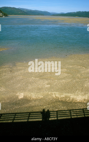 Schatten der beiden Figuren am Bahnhof Steg mit Blick auf die Mündung des Flusses, Afon Mawddach, Barmouth, Wales Stockfoto