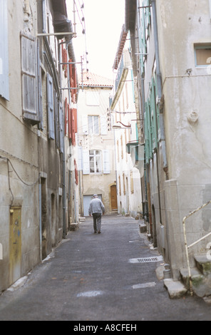 Rückansicht der ältere Mann zu Fuß durch eine schmale alte Gasse in einer kleinen Stadt in Frankreich Stockfoto