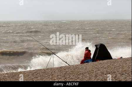 Meer-Angler mit stürmischer See Sandgate Strand Kent Stockfoto