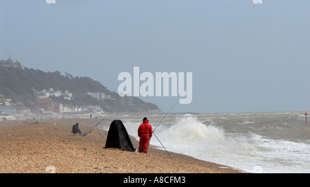 Meer-Angler mit stürmischer See Sandgate Strand Kent Stockfoto