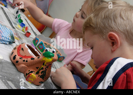 zwei Kinder dekorieren Tontöpfe mit Lacken Stockfoto
