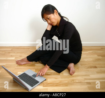 entspannende orientalische Frau auf Holzboden mit Laptop-computer Stockfoto
