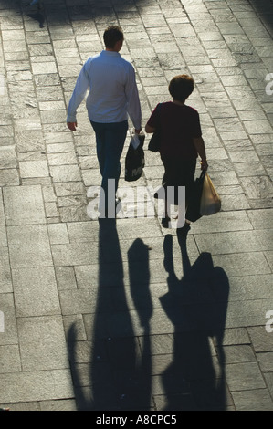 Western Australia Perth ältere Paare, die mit Einkaufstüten über geflieste Platz schaffen lange Schatten in niedrigen Nachmittagssonne Stockfoto