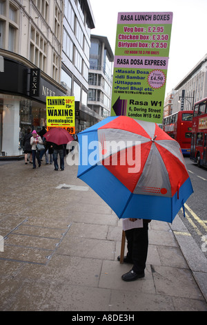 Zwei Sandwichbrett Männer Werbung Geschäfte Unterschlupf unter Sonnenschirmen in der Londoner Oxford Street Stockfoto