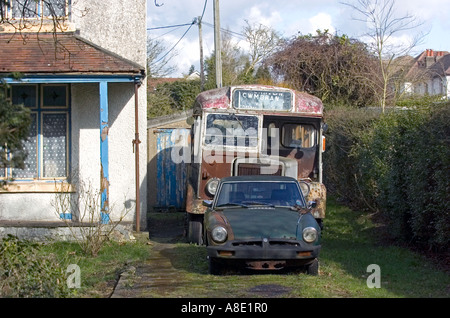 Alte Sportwagen und Oldtimer Bus außerhalb heruntergekommenen Haus in Chepstow Stockfoto