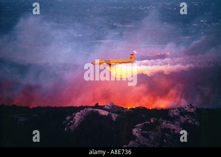 Luftaufnahme von eine Douglas DC-6B Löschwasser bomber Flugzeug fallen Feuerhemmende über ein wildfire bei Dämmerung, Flammen, Provence, Frankreich, Europa, Stockfoto